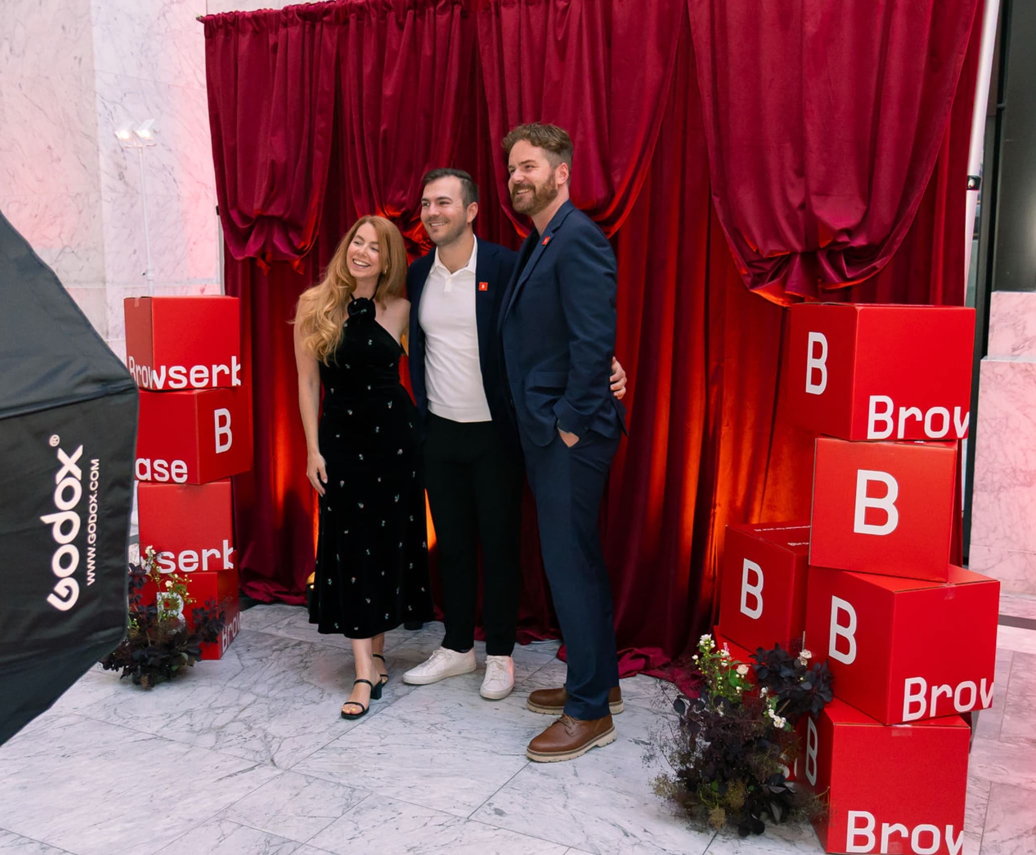 Three guests posing in front of a stacked red Browserbase B cube photo booth backdrop